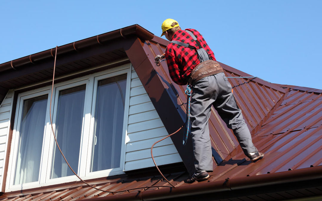 roofer builder worker spraying paint on metal sheet roof