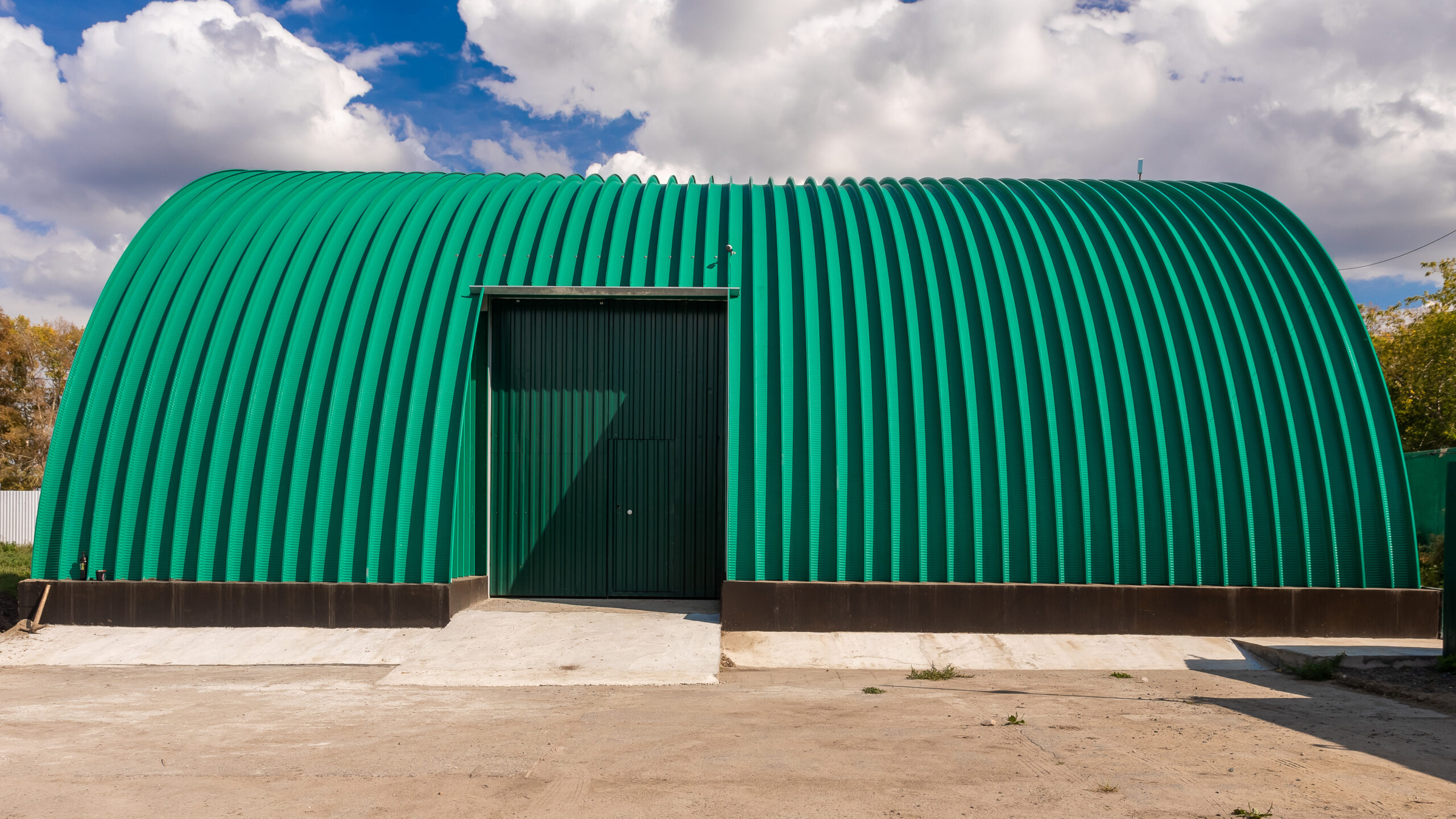 Facade of a green metal warehouse, commercial building for storage of goods. The concept of storage of goods by importers, exporters, wholesalers, transport enterprises, customs aerial drone inspection of roof